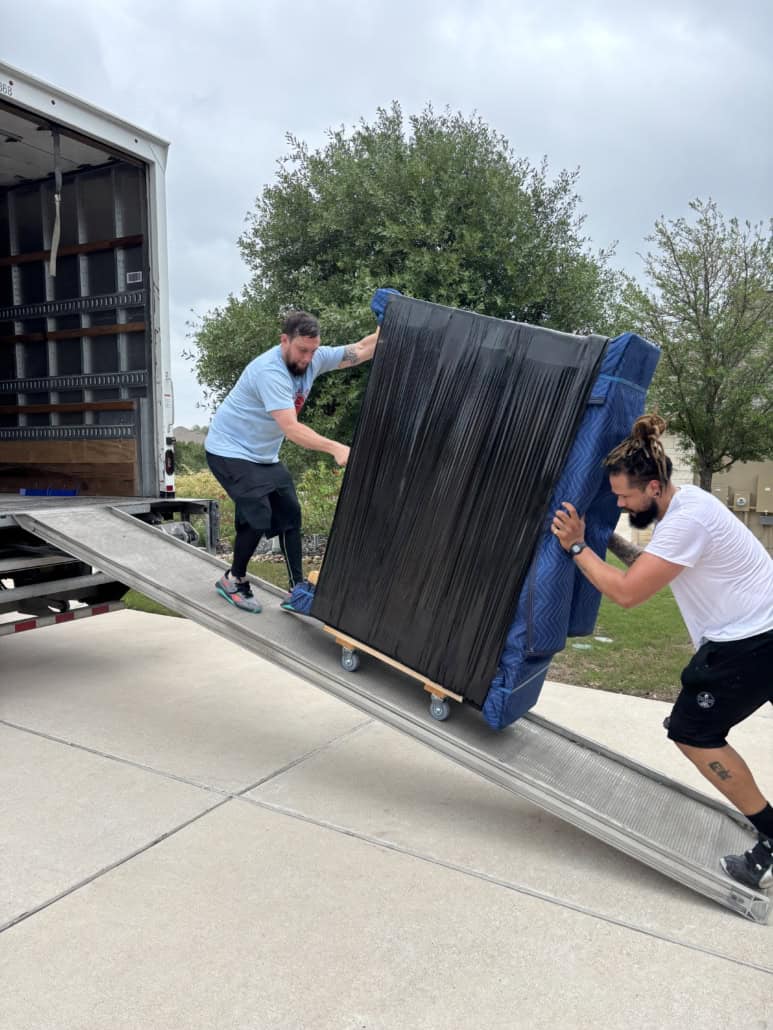 Efficient movers loading a large mattress onto a moving truck.